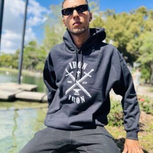 A boy wearing a black sweatshirt sitting on a wall