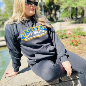 A girl wearing a black sweatshirt sitting on a wall